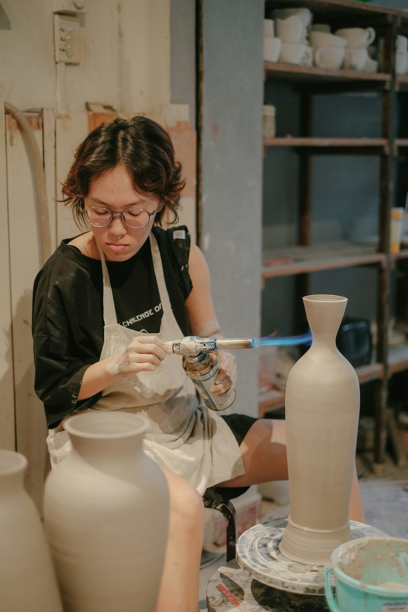 a woman is making a vase out of clay